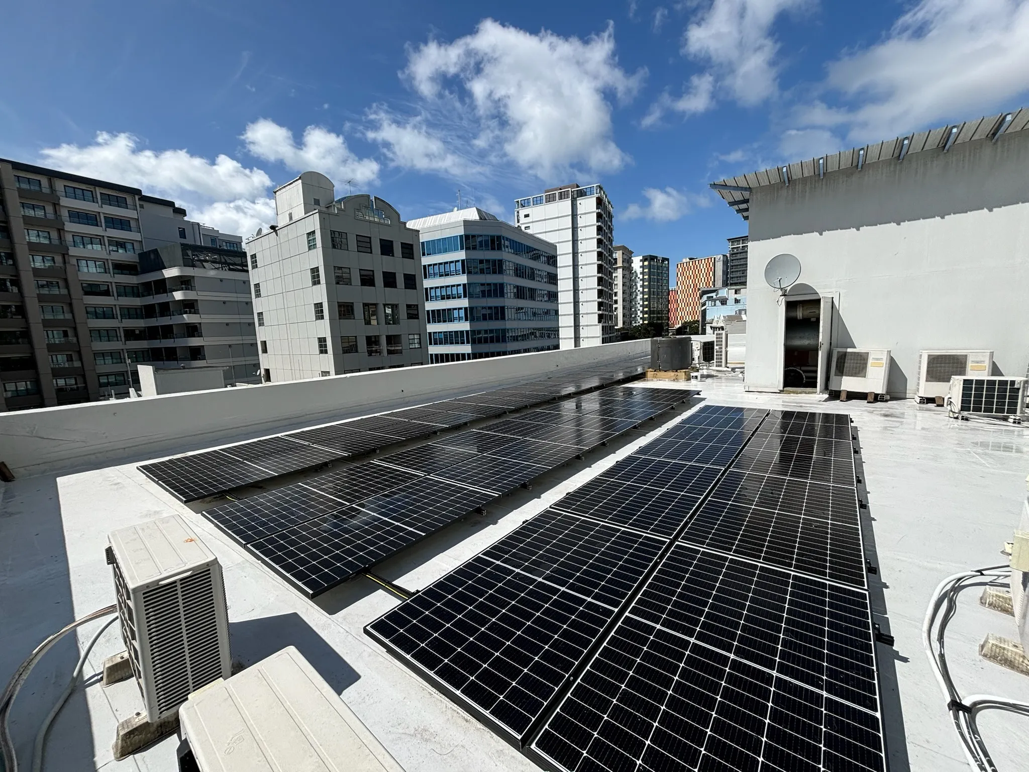 Rooftop solar array on a commercial building with Auckland city high-rises behind