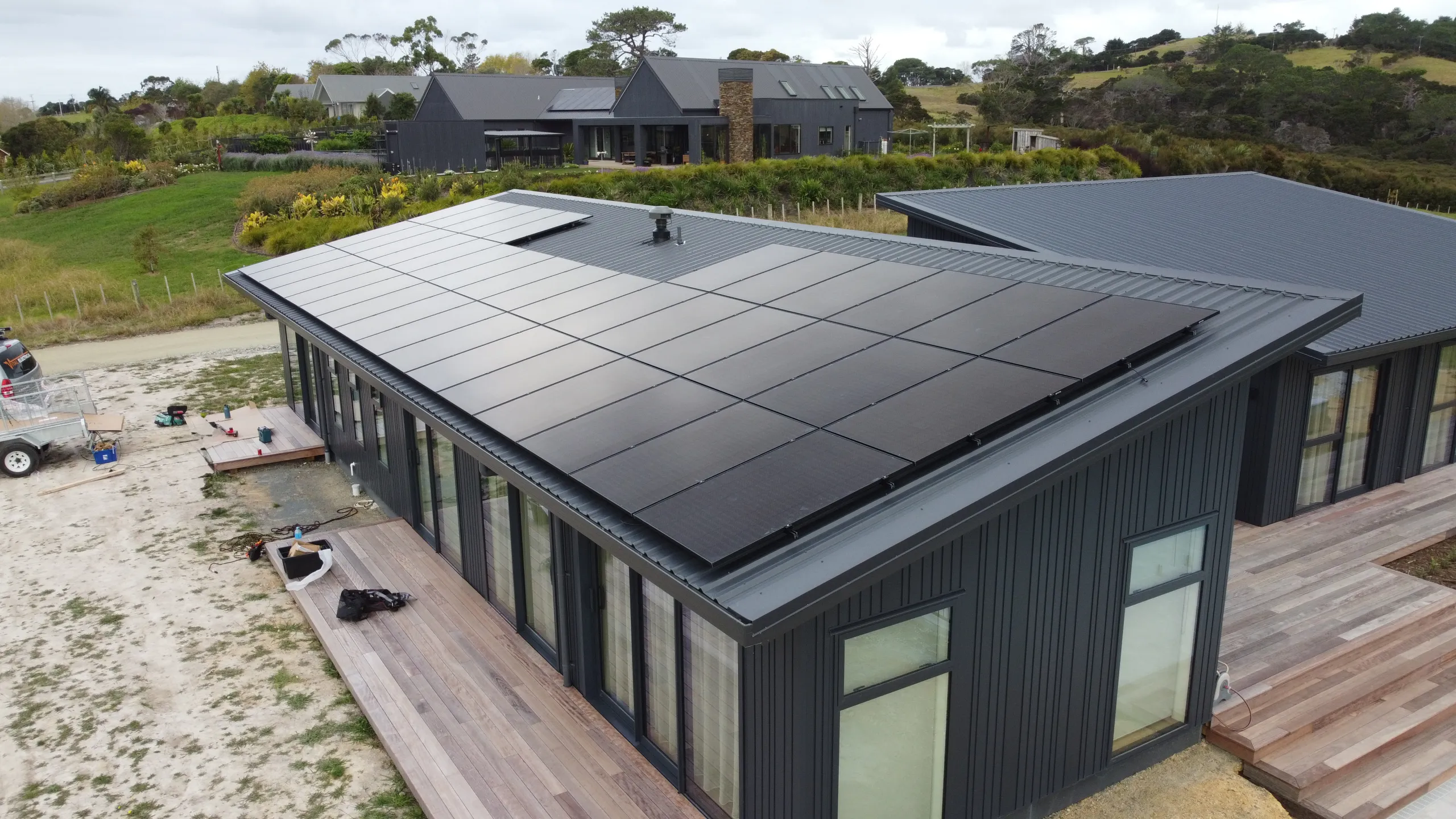 Full-roof black solar array installed by Vital Energy on a modern Auckland home, aerial view